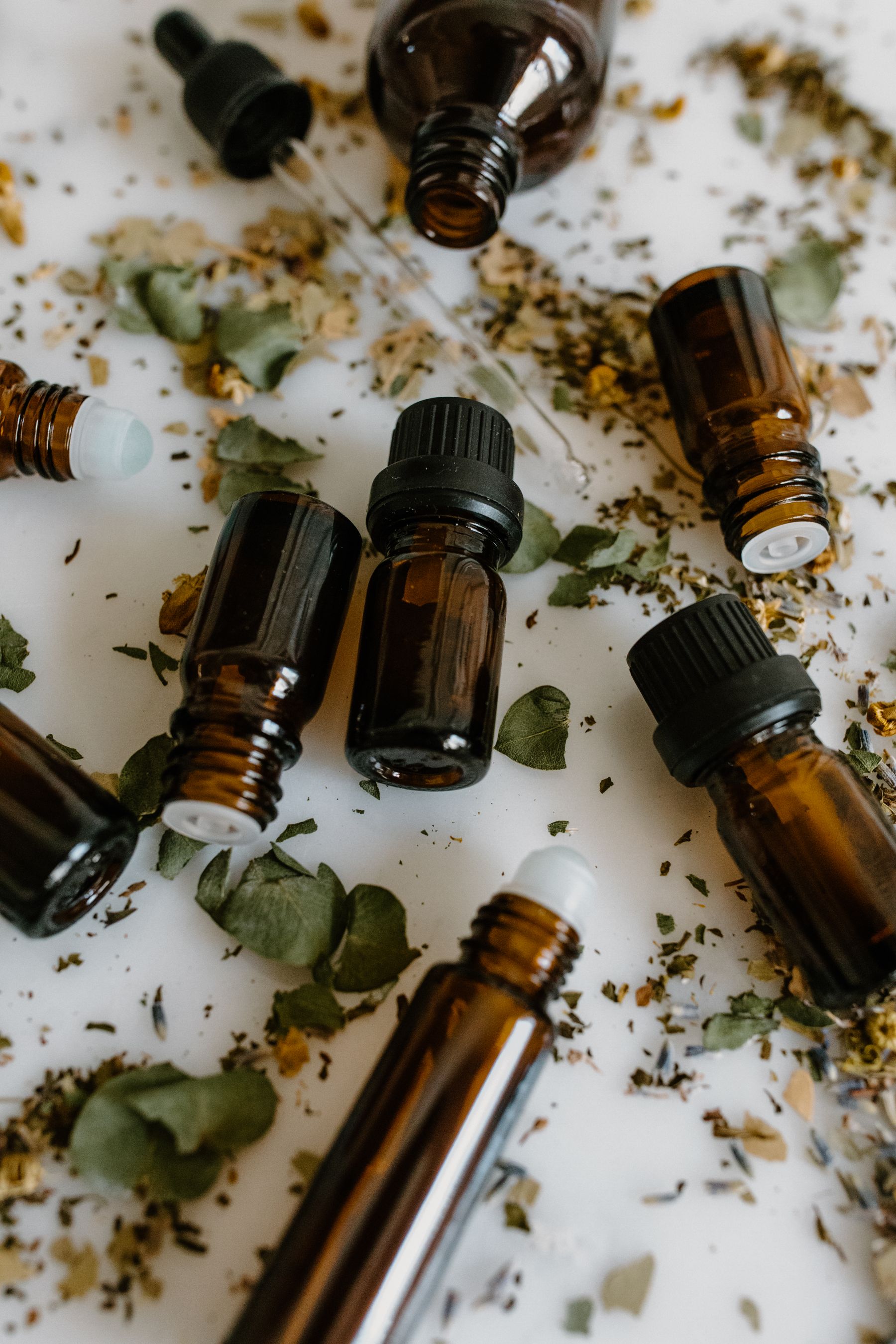 Amber glass vials, dried herbs and a pipette on a table